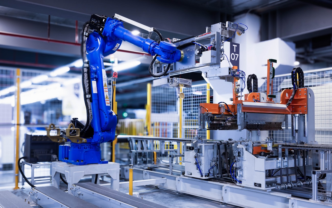 A robot arm loading trays into an environmental burn-in chamber on a production line