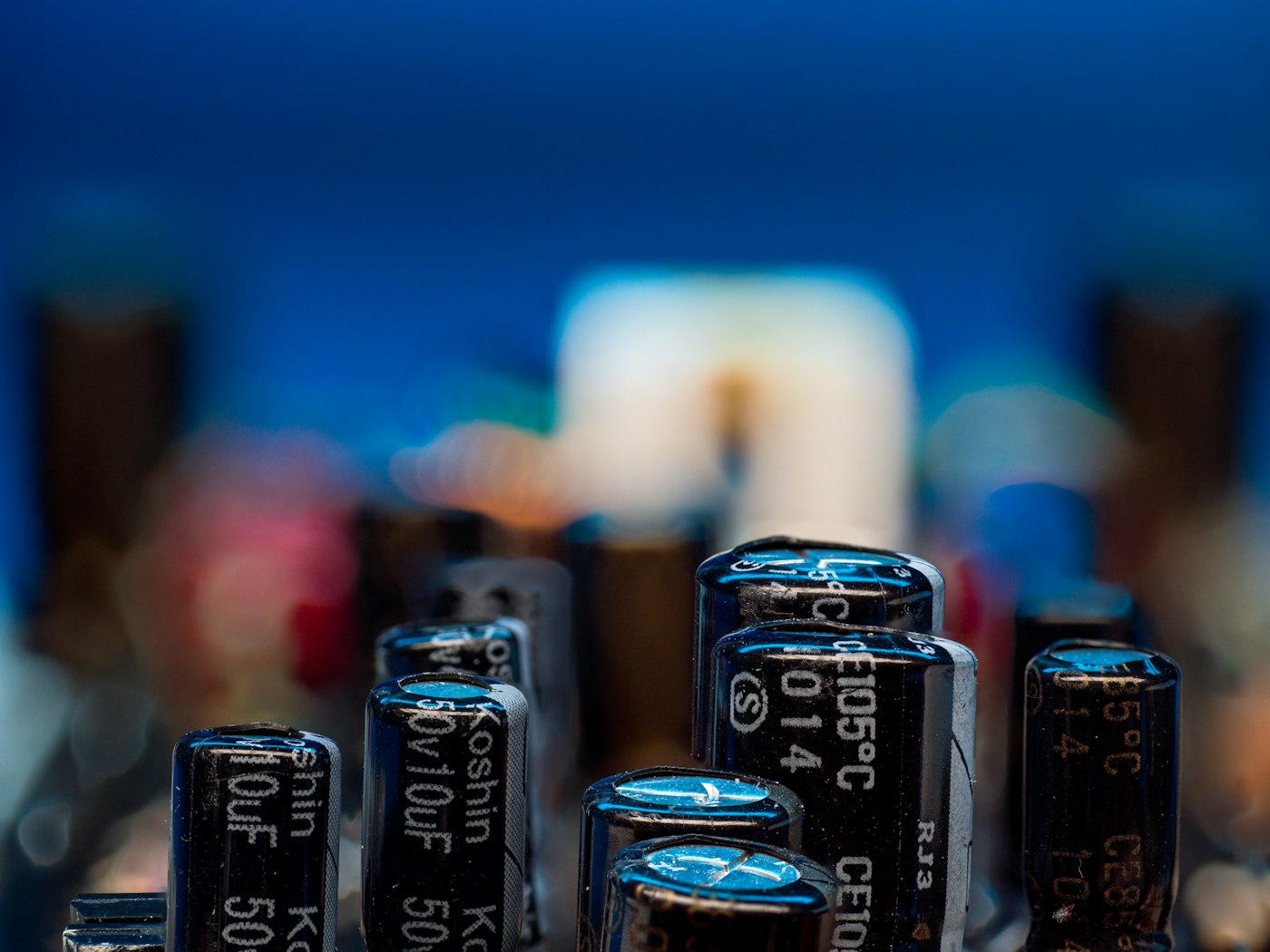 Electrolytic capacitors standing on a circuit board, 105 degree ratings printed on their sleeves