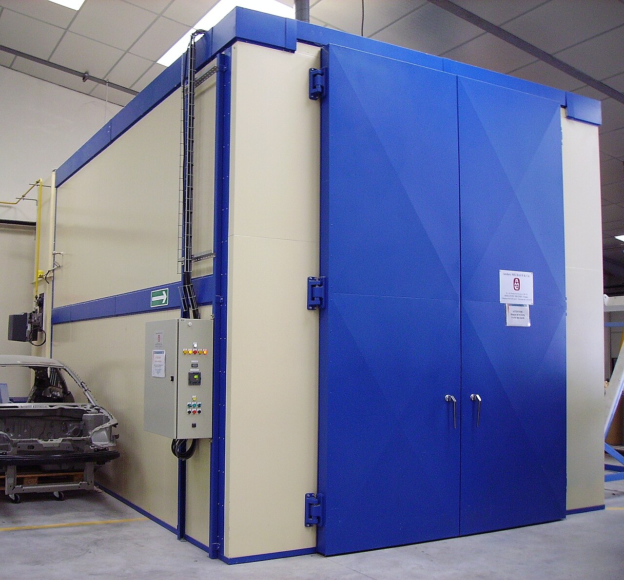 A large walk-in industrial dry heat oven with double doors and a control panel, used to heat large products