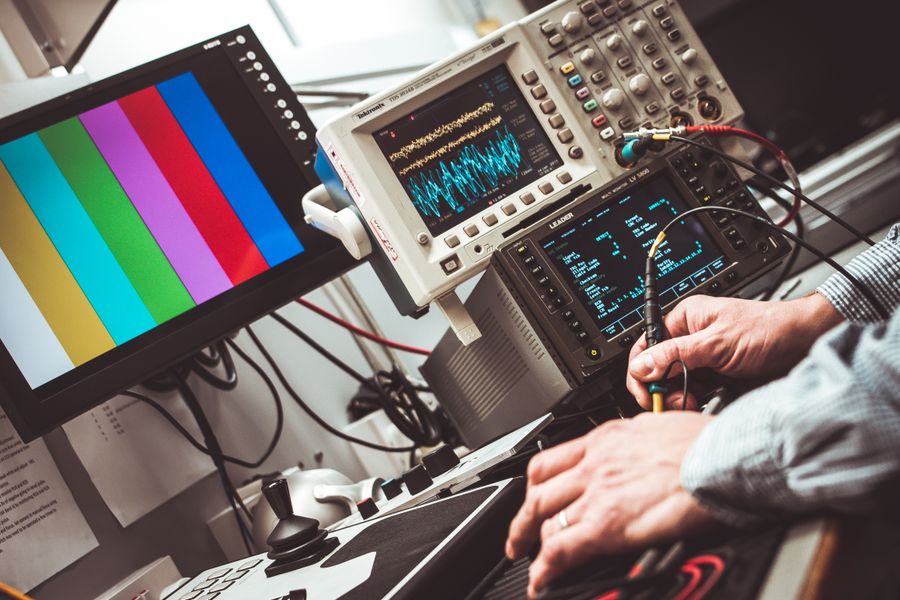 Engineer probing a circuit with an oscilloscope, waveforms on the screens