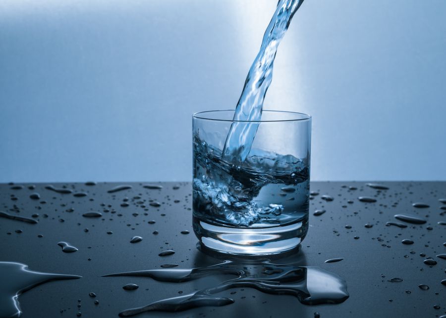 Clear water poured into a glass on a wet dark surface