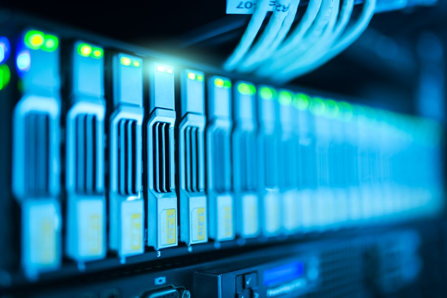Row of server blades in a rack lit blue with green status lights
