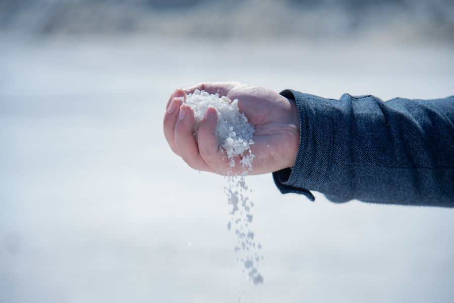 A hand pouring coarse white salt crystals