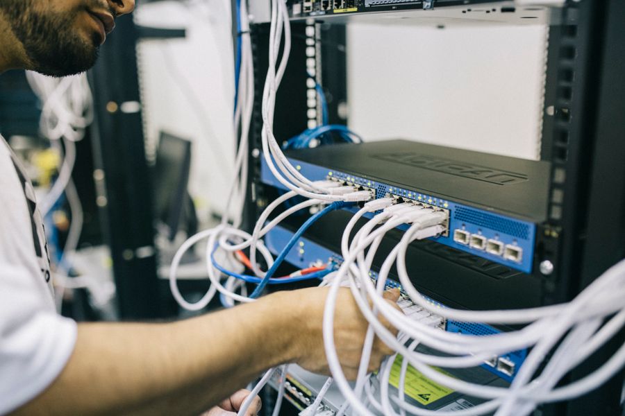 Technician connecting cables at the back of a server rack