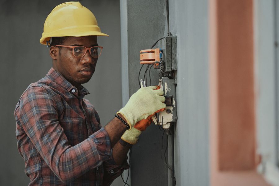 Technician checking wiring at an electrical panel on a wall