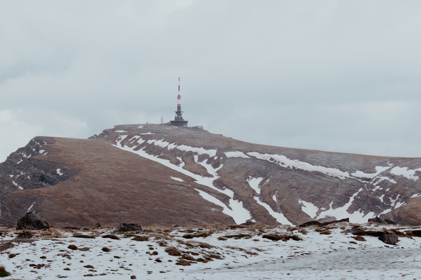 Communication tower standing on a snow-patched plateau ridge