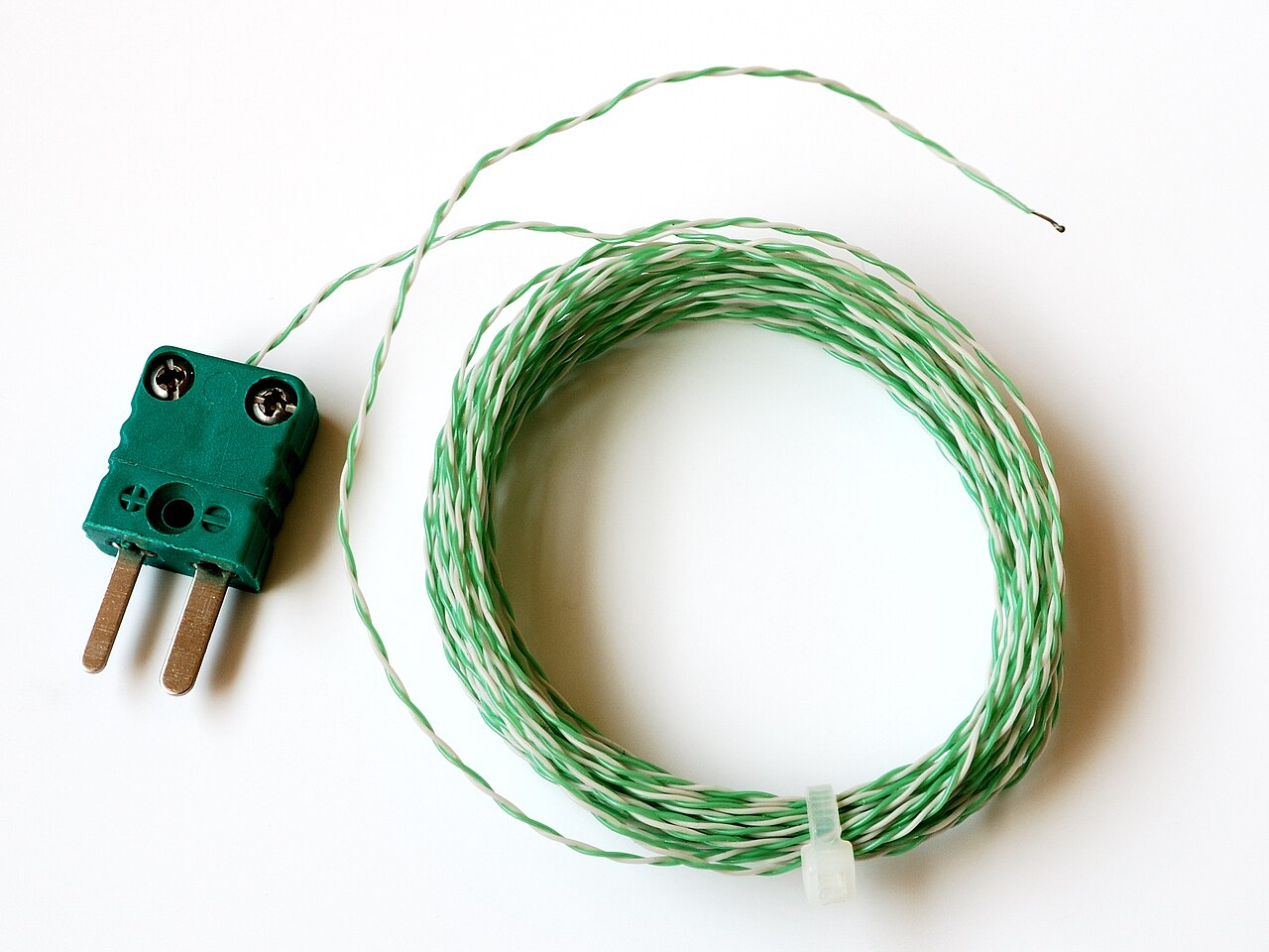 A green Type K thermocouple connector with twisted green and white measuring wire