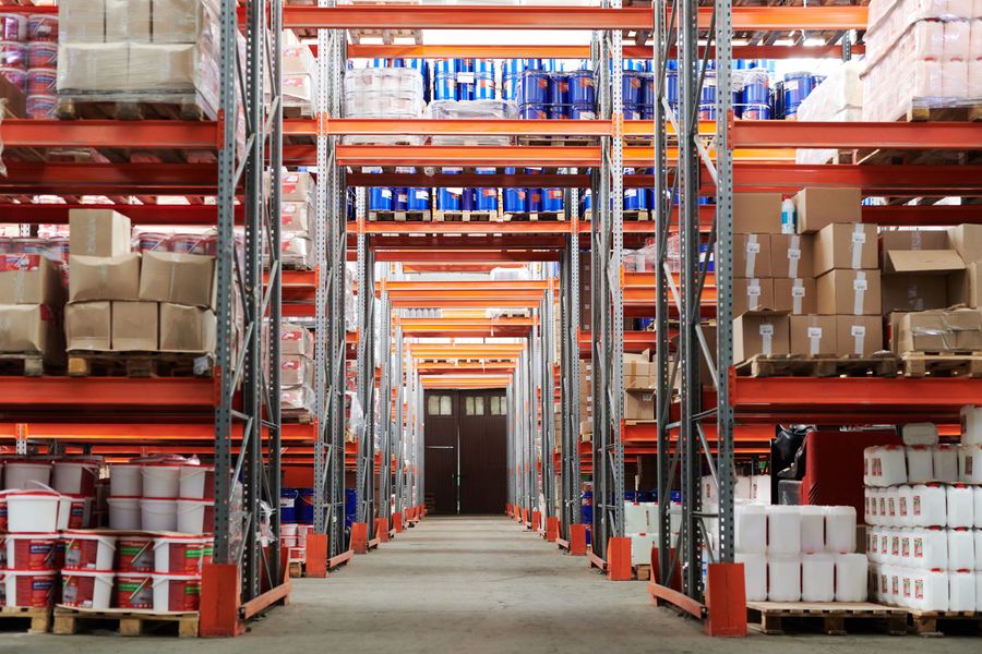 Warehouse aisle between tall pallet racks loaded with boxed goods