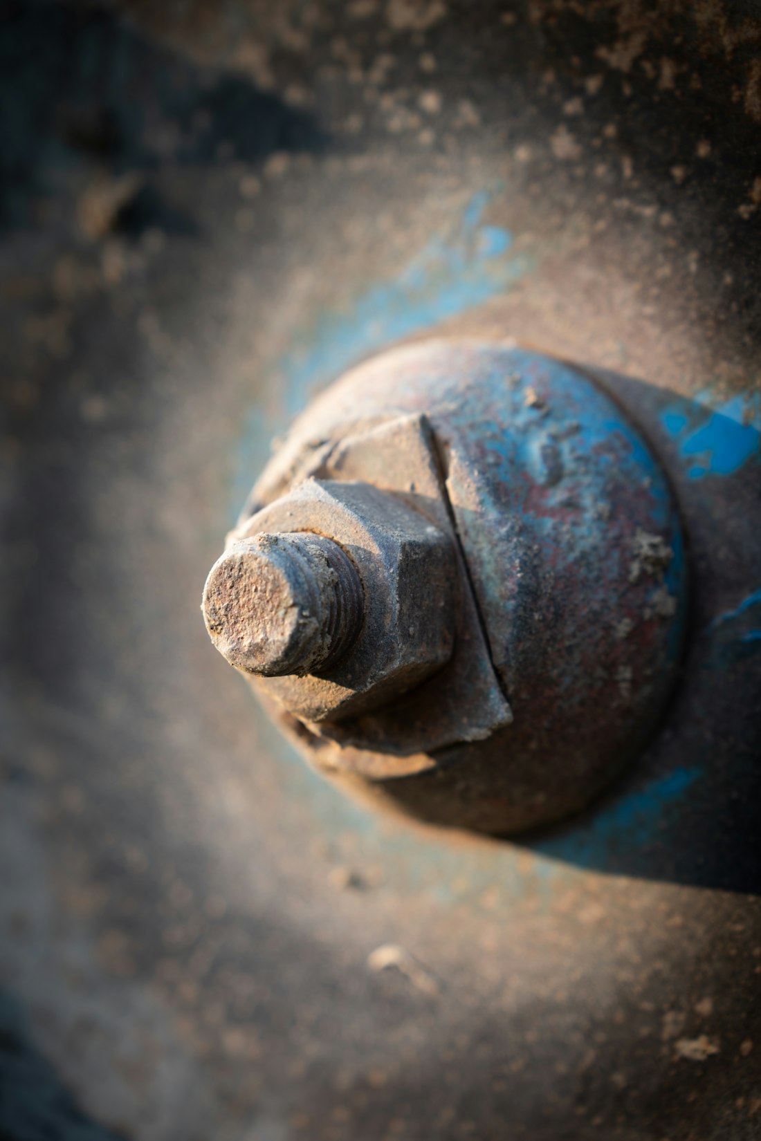 Rust layers with chipped blue paint on a weathered bolt in close view